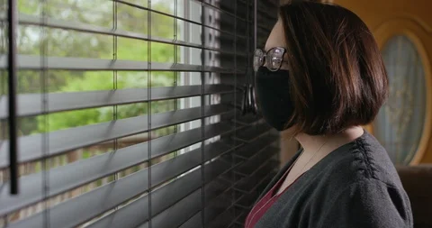 Woman Looking Out Of Window While Wearing Homemade Protective Face Mask PPE Vídeo Stock 129564844
