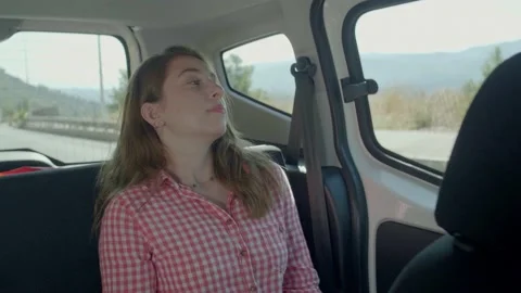 A woman is looking out the window while sitting in the back seat of the car. Stock Footage 144325154