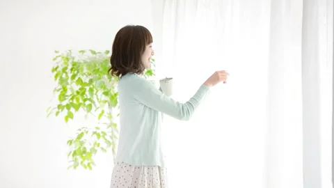 Woman looking out of the window while drinking coffee Stock Footage 160127605
