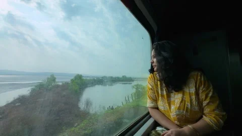 Woman looking outside train window enjoying scenic journey of indian konkan Stock Footage 335275226