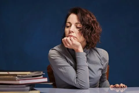 Woman looking at stack of papers at her desk with no desire to work Stock Photos