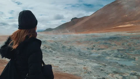 Woman looking at steaming mud pools and fumaroles in the Hverir geothermal area Stock Footage 321040991