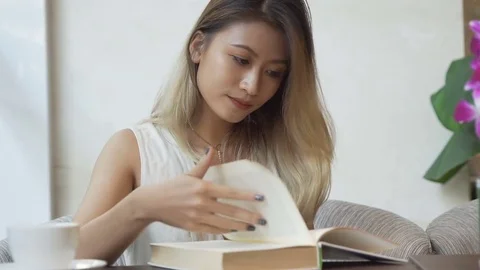 Woman looking through dictionary and drinking coffee. Stock Footage 79372175