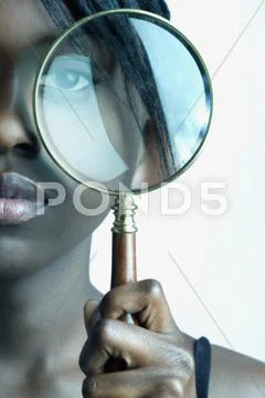Woman looking through magnifying glass Stock Photos