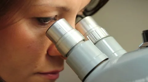 Woman looking through a microscope Stock Footage 8570463