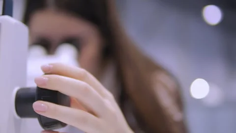 A woman is looking through a microscope Stock Footage 297733301