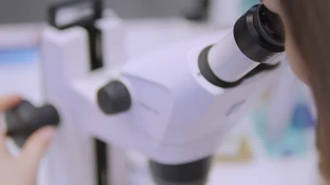 Woman is looking through a microscope Stock Footage 297978701