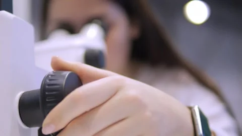Woman is looking through a microscope Stock Footage 299571939