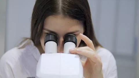 Woman is looking through a microscope Stock Footage 299572004