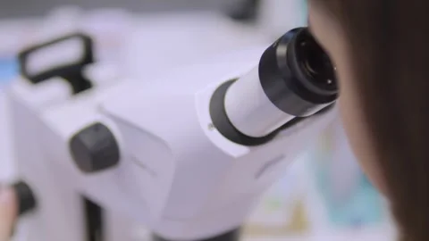 Woman is looking through a microscope Stock Footage 299572122