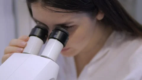Woman is looking through a microscope Stock Footage 299881094
