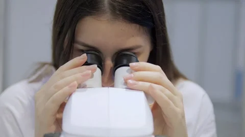 Woman is looking through a microscope Stock Footage 299881100