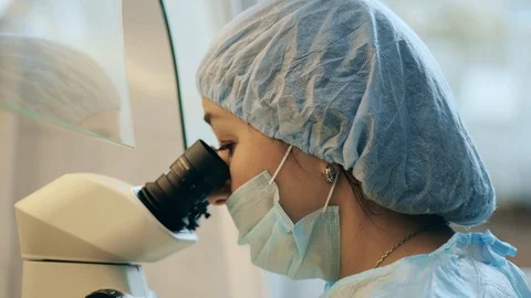 A woman is looking through the microscope oculars Stock Footage 119693834