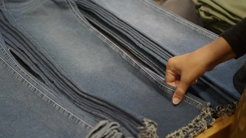 A woman is looking through a stack of folded jeans in a store Stock Footage 346194803