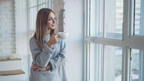 Woman looking in window and drinking tea Stock Footage 100041832