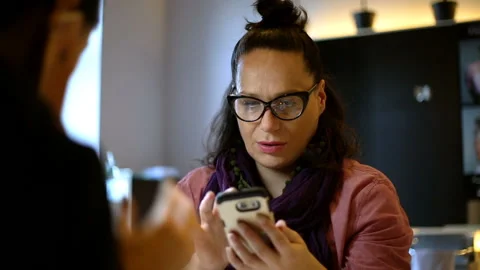 Woman looks absorbed while browsing internet on smartphone in the beauty saloon Stock Footage 86216299