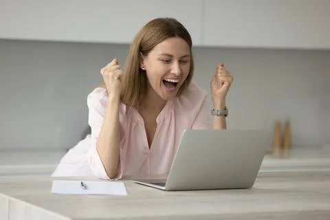 Woman looks at laptop scream with joy while read news Stock Photos