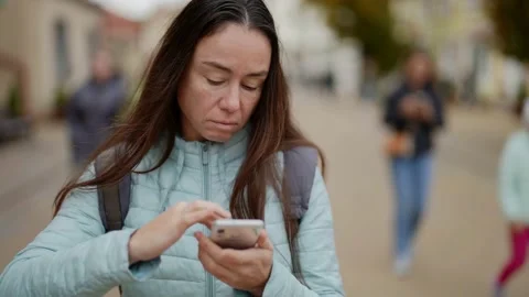 A woman looks at a map in the phone app, trying to find her way. An adult woman Vídeo Stock 163404953