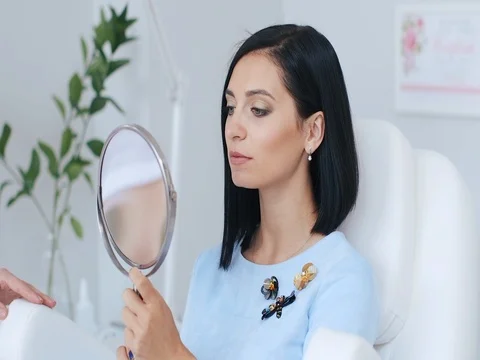 Woman looks in the mirror effect of cosmetic surgery. Stock Footage 74381663