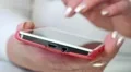 Woman looks the photos in smartphone. Woman holds red mobile phone HD Footage