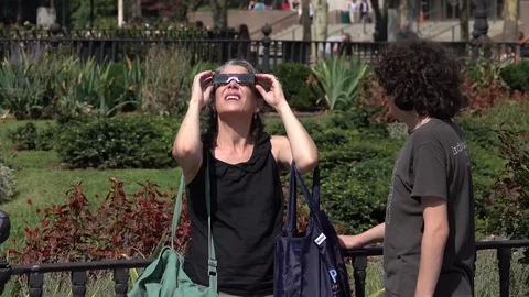 A woman looks at a solar eclipse through glasses Stock Footage 79830679
