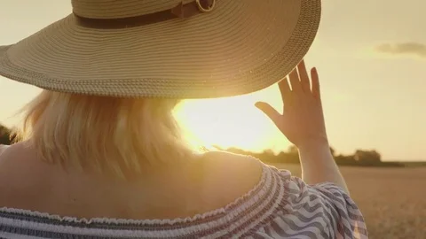 A woman looks at the sunset over the wheat field. He extends his hand to the sun Stock Footage