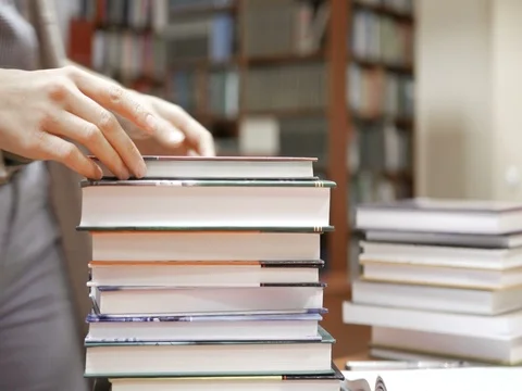 Woman looks through stack of books on the table Stock Footage 82201279