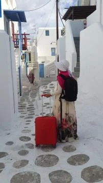 Woman with luggage walking in Mykonos, Greece Stock Photos