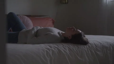Woman Lying Back On Bed Looking Up Lost In Thoughts Video stock 270332071