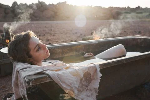 Woman lying in the bath in the desert Stock Photos