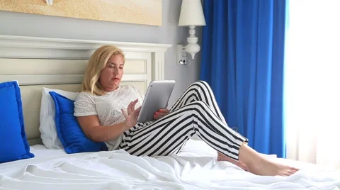 Woman lying on a bed and using i pad 2 Stock Footage 64761229