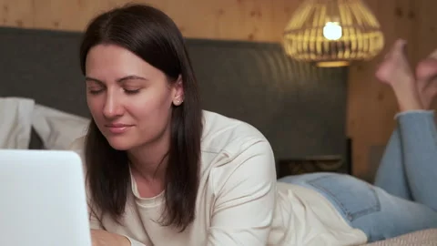 Woman lying on bed using laptop in hotel room Stock Footage 303497166