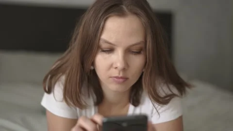 Woman lying on bed using smartphone at home in bedroom Stock Footage 132047436