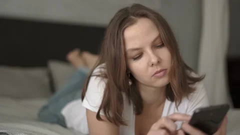 Woman lying on bed using smartphone at home in bedroom Stock Footage 132049002
