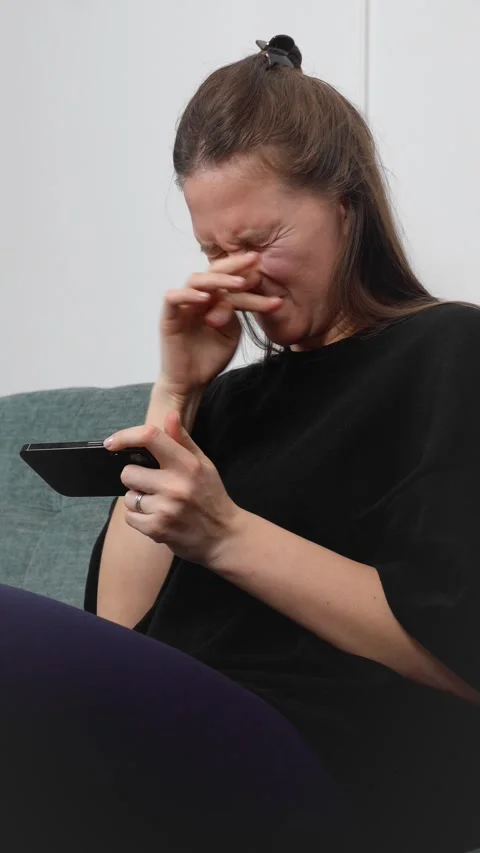 Woman lying on couch playing mobile game with enthusiasm 库存影片 308236340
