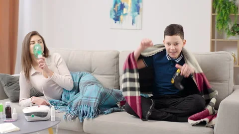 Woman is lying on the couch using an inhalation nebulizer at home Stock-Footage 268823609