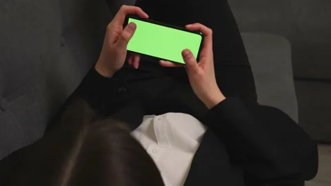 Woman lying on a Couch using Smartphone with Green Mock-up Screen, playing game Stock Footage 150167925