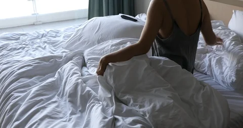 Woman lying down and using TV remote control and smartphone on bed Video stock 112241467