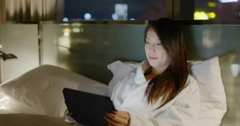 Woman lying down on bed and read on tablet computer Video stock 164080562