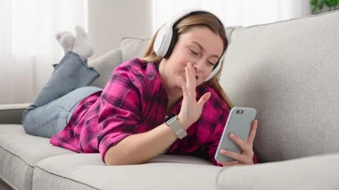 Woman lying down on sofa and having video call Stock Footage 233464347