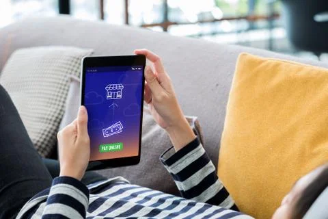 Woman lying down on sofa using tablet banking app pay bill online at home.dig Stock Photos