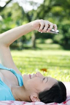 Woman lying down while looking at her mobile phone Stock Photos
