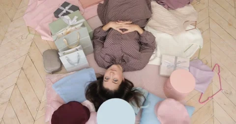 Woman is lying on the floor surrounded by things, boxes, bags and clothes. Stock Footage 146679331