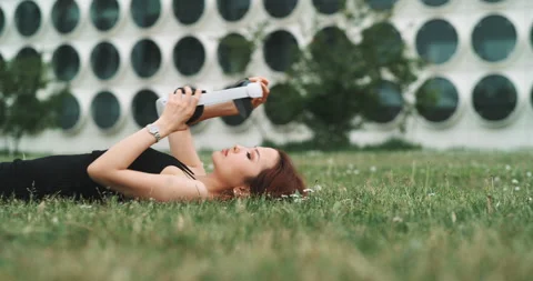 A woman lying on the grass while trying virtual reality glasses Stock Footage 201117520