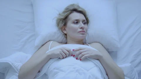 Woman lying in her comfortable bed thinking about something and falling asleep Stock Footage 255132989