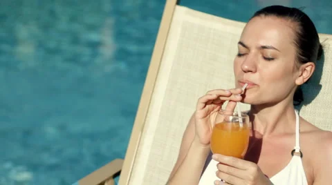 Woman lying by the pool and drinking exotic drink Stock Footage