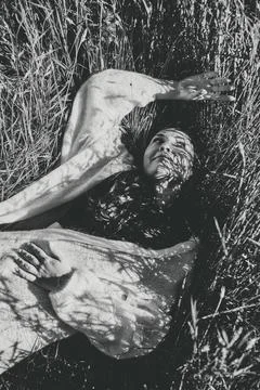 Woman lying in rye field with patterned shadows in black - And - White Stockfoto's