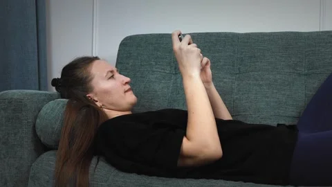 Woman lying on sofa using smartphone Stock Footage 308233986