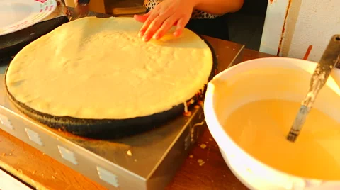 Woman make a pancakes on the metal plate stove on the street Stock Footage