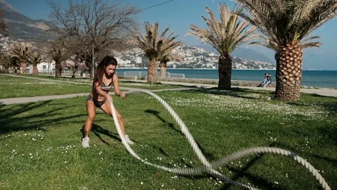 Woman makes exercise with two ropes holding in arms, moving fastly standing on Video stock 77284699
